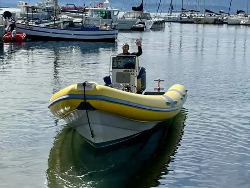 Un homme salue depuis un bateau semi-rigide jaune et blanc en mer