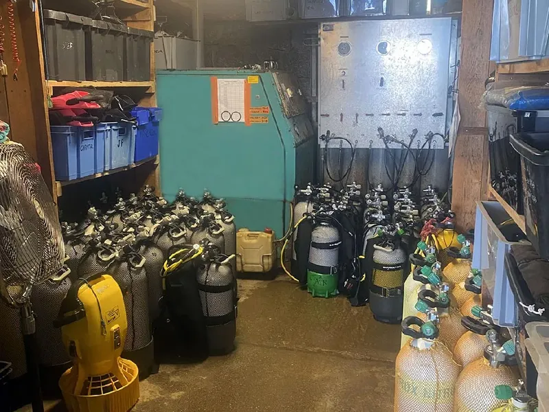 Nombreuses bouteilles de plongée et équipements dans un local sombre