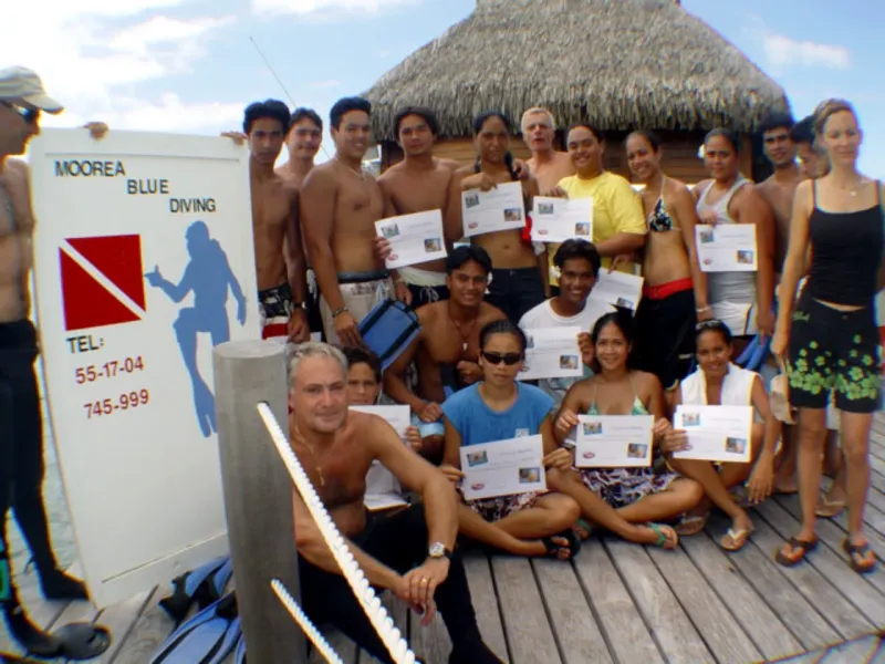 Groupe de plongeurs souriants posant avec leurs certificats sur un ponton