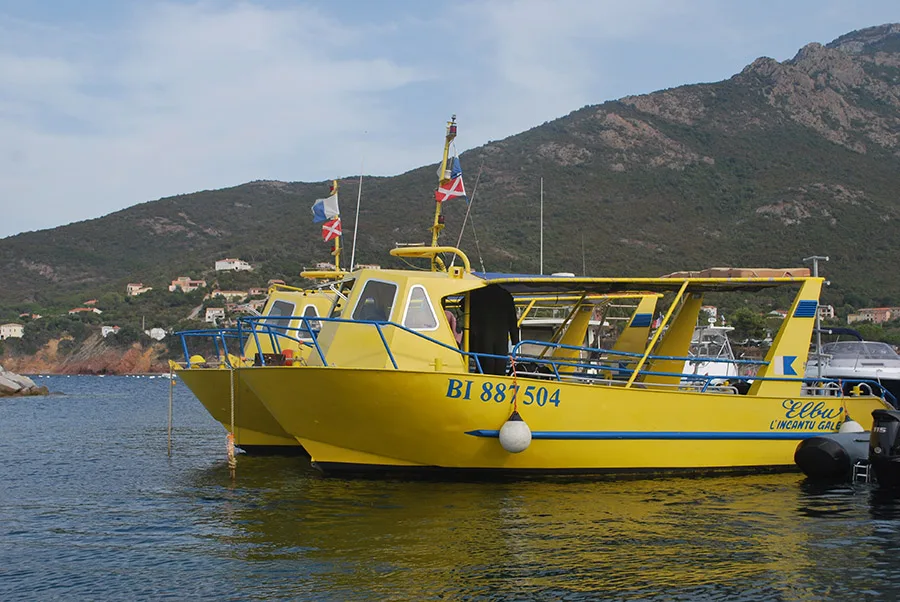 Bateau jaune amarré dans un port avec des collines en arrière-plan