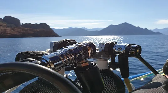 Lampe de plongée fixée sur un bateau en mer, paysage montagneux