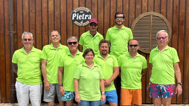 Groupe de personnes souriantes devant un mur en bois et une enseigne
