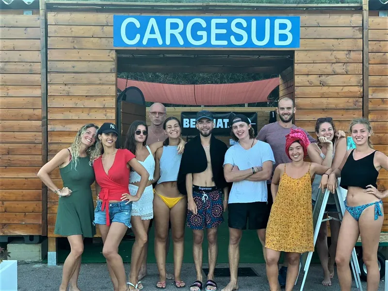 Groupe de personnes souriantes devant la devanture d'un centre de plongée