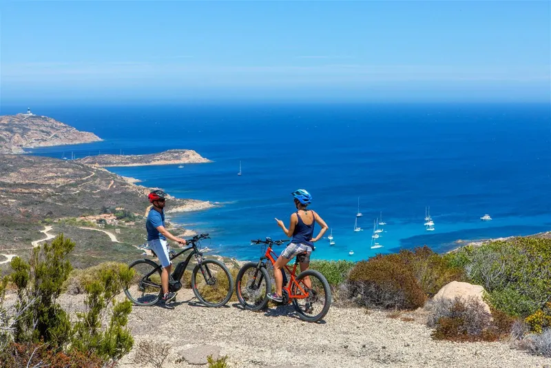 Deux cyclistes admirent la vue sur la mer et les bateaux