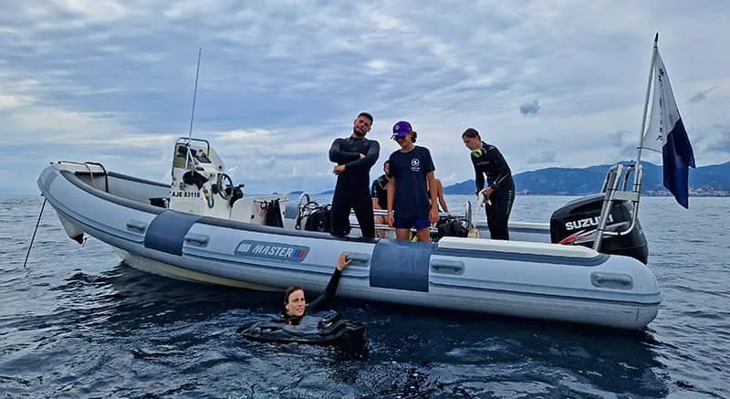 Plongeurs sur un bateau semi-rigide, une personne nage en avant