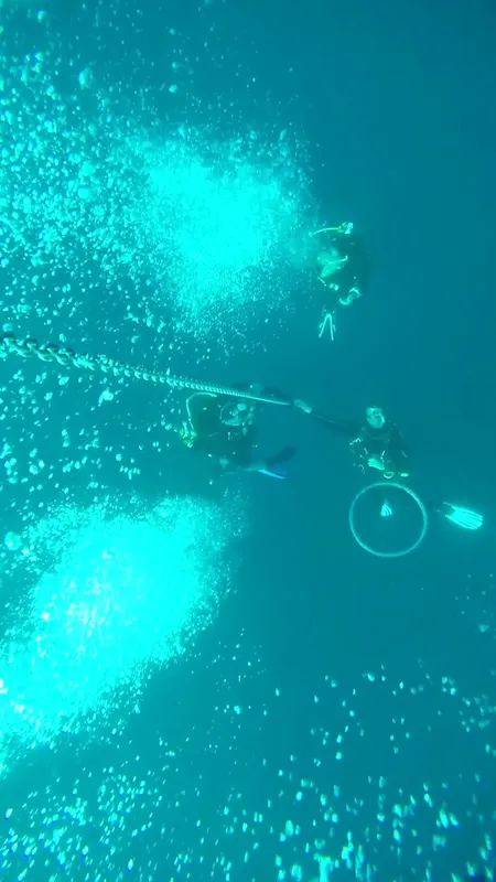 Plongeurs en exploration sous-marine, bulles et lumière turquoise ambiante