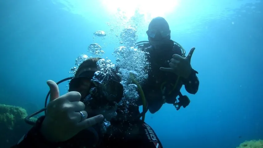 Deux plongeurs souriants font le signe 'ok' sous l'eau