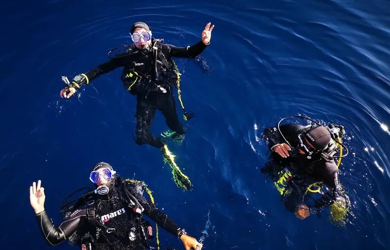 Trois plongeurs en combinaison explorent les profondeurs marines avec joie