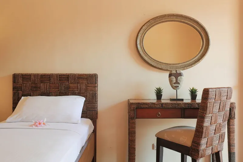 Chambre avec lit simple, coiffeuse, miroir et décoration ethnique