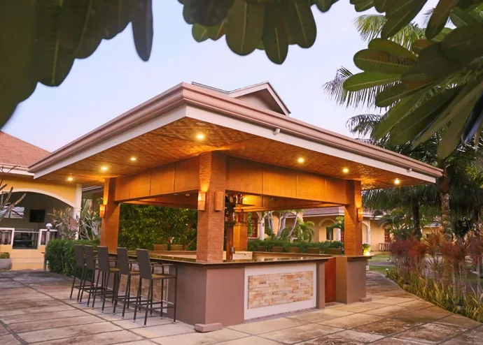 Bar extérieur avec comptoir, éclairage et végétation tropicale environnante