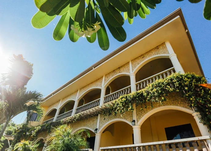 Bâtiment jaune à arcades fleuries sous un ciel bleu ensoleillé