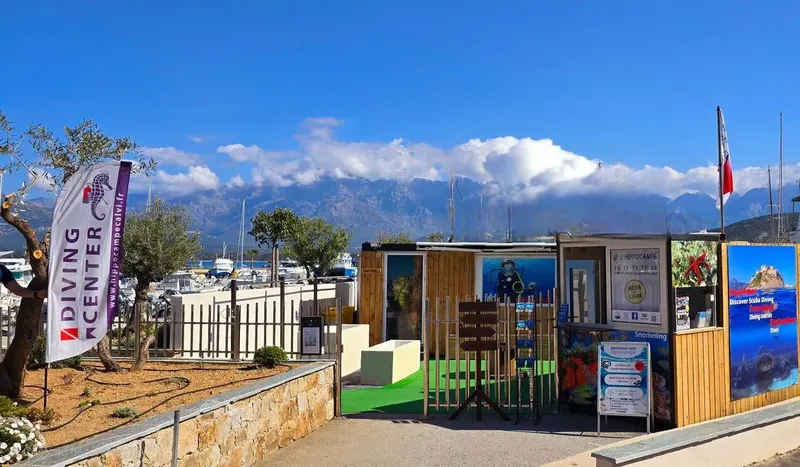 Devanture d'un centre de plongée avec bateau et montagne en arrière-plan