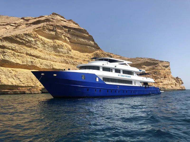 Grand bateau de plongée bleu et blanc amarré près de falaises