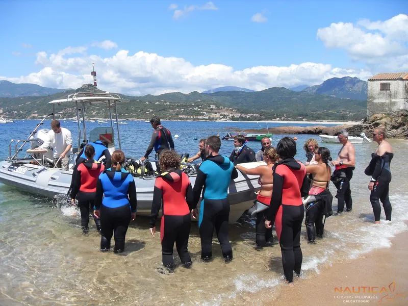 Groupe de plongeurs s'apprêtant à embarquer sur un bateau pneumatique ensoleillé