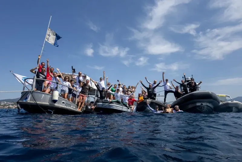 Groupe de personnes sur des bateaux de plongée, bras levés, joie