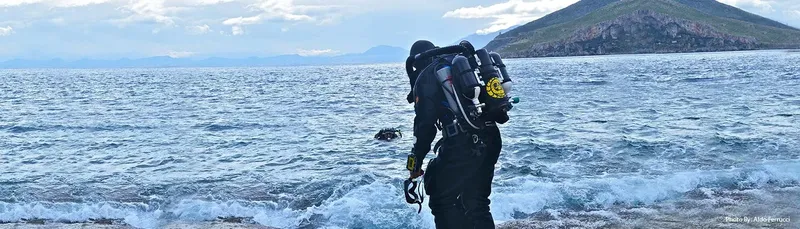 Plongeur préparant son équipement sur une plage rocheuse ensoleillée