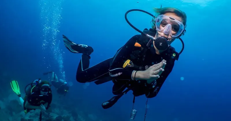 Plongeuses en combinaison explorent les fonds marins, bulles et visibilité