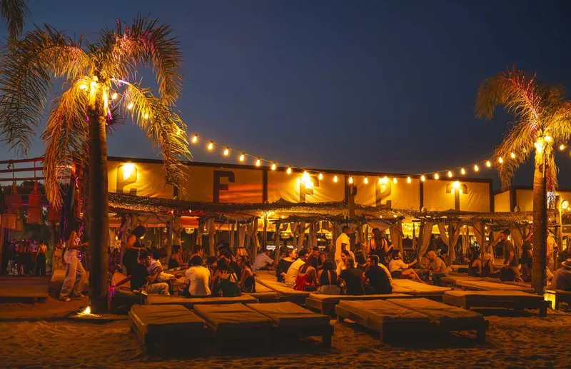 Ambiance nocturne sur une plage avec des personnes assises et allongées