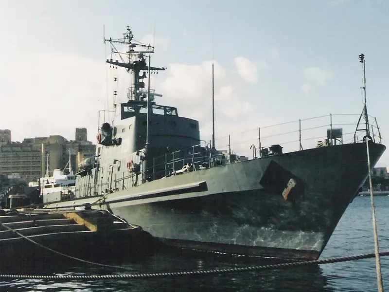 Bateau gris amarré au port avec bâtiments en arrière-plan