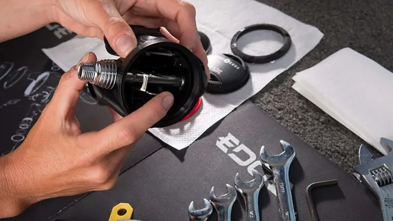 Mains manipulant un détendeur de plongée avec des outils à proximité