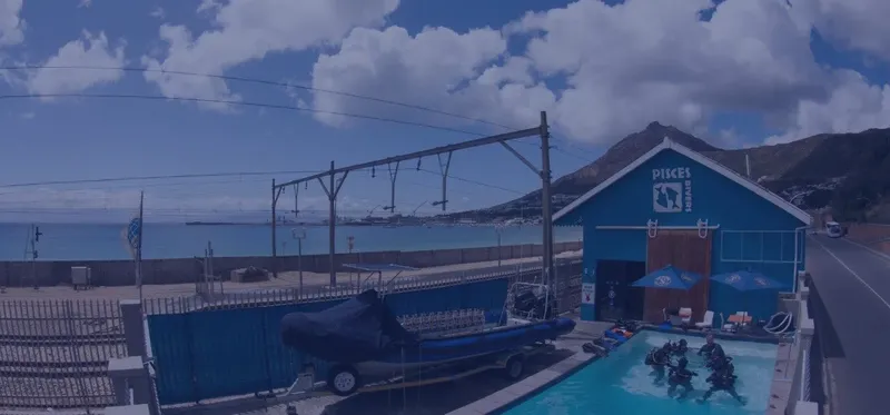 Bâtiment bleu, piscine, bateau sur remorque, personnes équipées, ciel nuageux