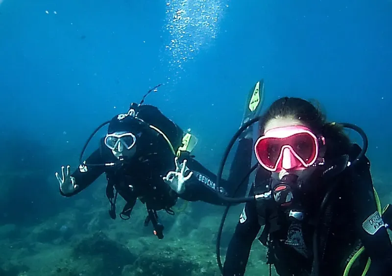 Deux plongeurs en combinaison explorent les fonds marins bleus