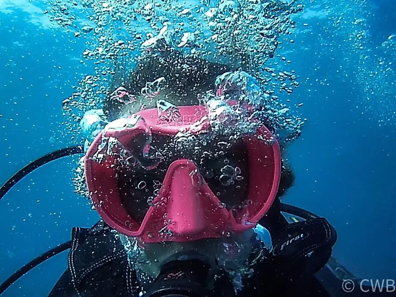 Plongeur avec masque rose, bulles d'air, immersion en milieu bleu