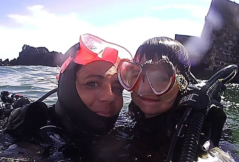 Deux plongeuses souriantes en combinaison et masque, prise de vue rapprochée