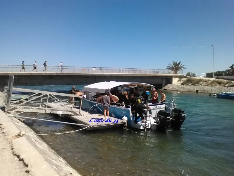 Bateau de plongée amarré avec des plongeurs équipés et un ponton d'accès