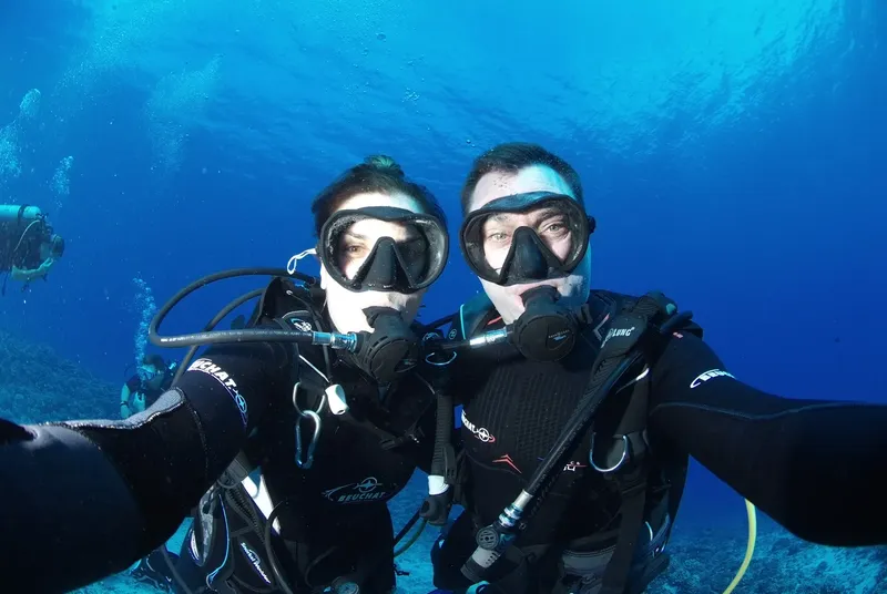 Deux plongeurs souriants se prennent en photo sous l'eau