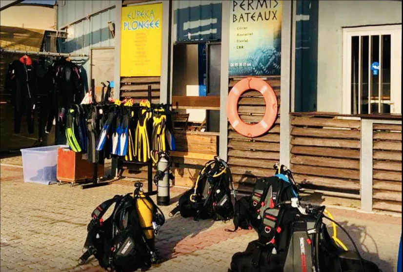 Equipement de plongée devant un centre, enseignes Eureka Plongée et Permis Bateaux