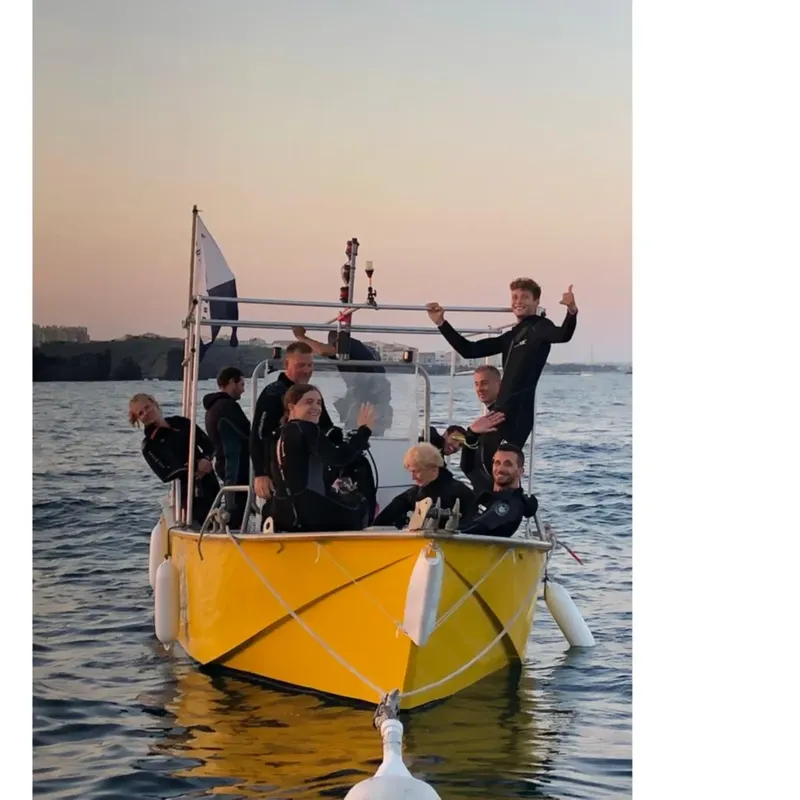 Groupe de plongeurs souriants à bord d'un bateau jaune en mer
