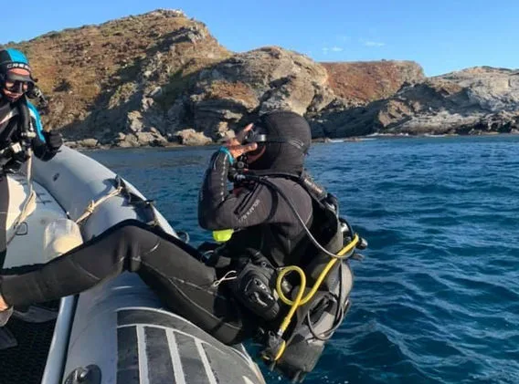 Plongeur en combinaison assis sur un bateau pneumatique en mer