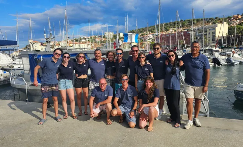 Groupe de personnes souriantes posant devant des bateaux dans un port