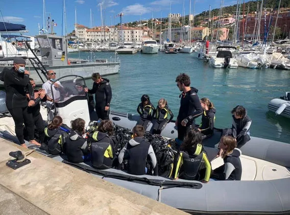 Groupe de plongeurs équipés sur un bateau dans un port ensoleillé