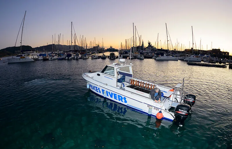 Bateau de plongée blanc avec des personnes à bord dans un port