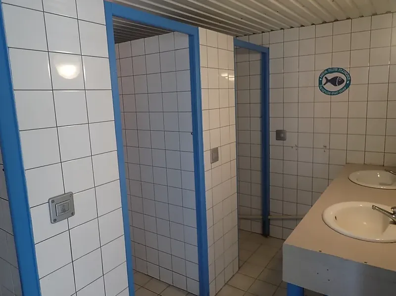 Sanitaires du centre de plongée avec carrelage blanc et lavabos