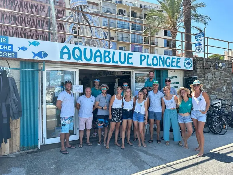 Equipe de plongée souriante devant la devanture d'un centre de plongée