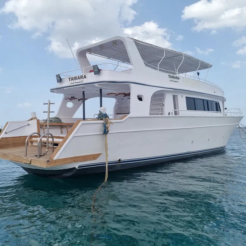 Bateau de plongée blanc amarré sur une mer bleue sous ciel nuageux