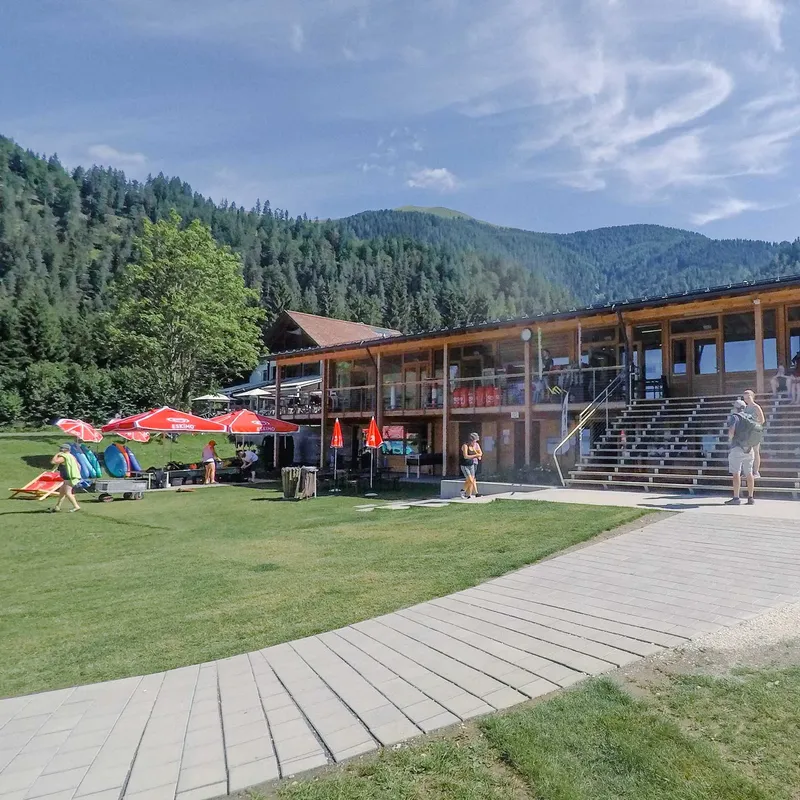 Bâtiment en bois avec pelouse, personnes se promènent et se détendent dehors