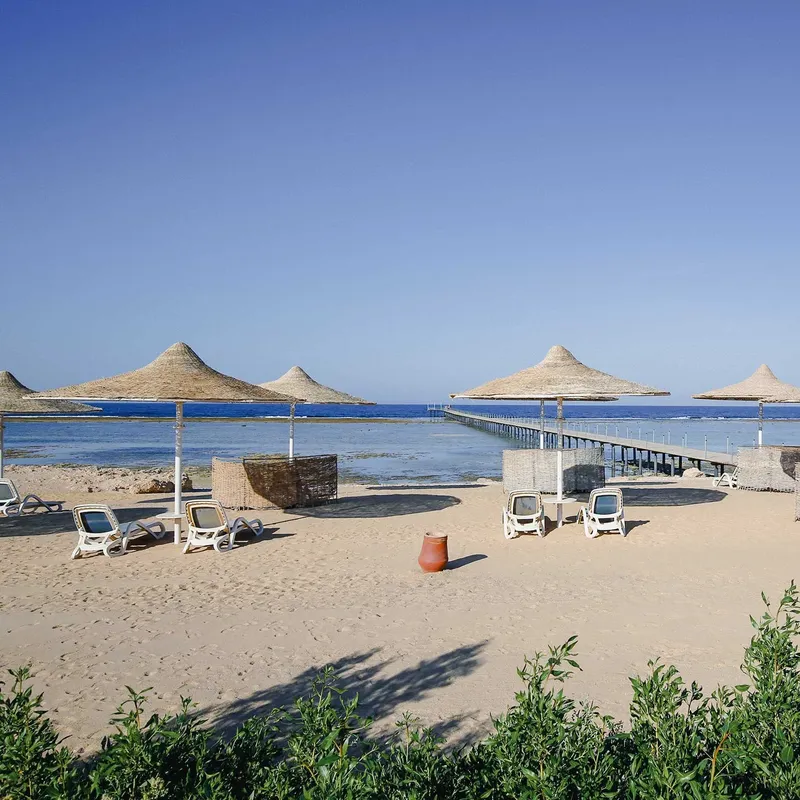 Plage de sable avec parasols, transats et un ponton en bois