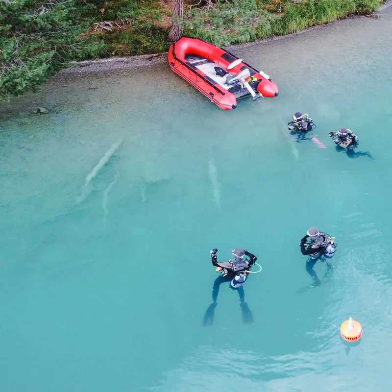 Plongeurs en combinaison noire explorent les eaux turquoise avec un bateau