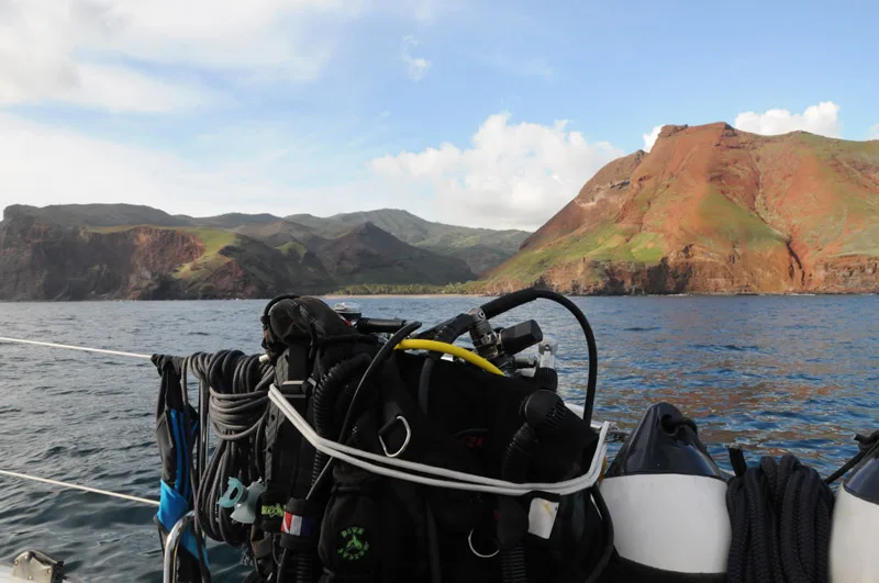 Equipement de plongée sur un bateau en mer, côte rocheuse verdoyante