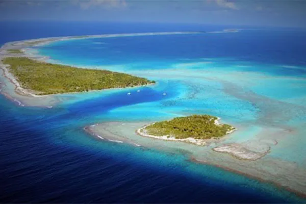 Vue aérienne d'un atoll tropical avec des eaux turquoise et des bateaux