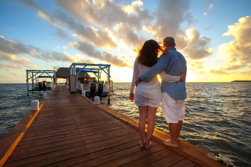 Couple se tenant sur un ponton au coucher du soleil en mer