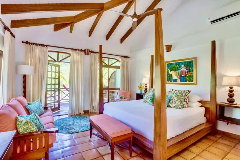 Chambre d'hôtel lumineuse avec lit à baldaquin et décoration tropicale