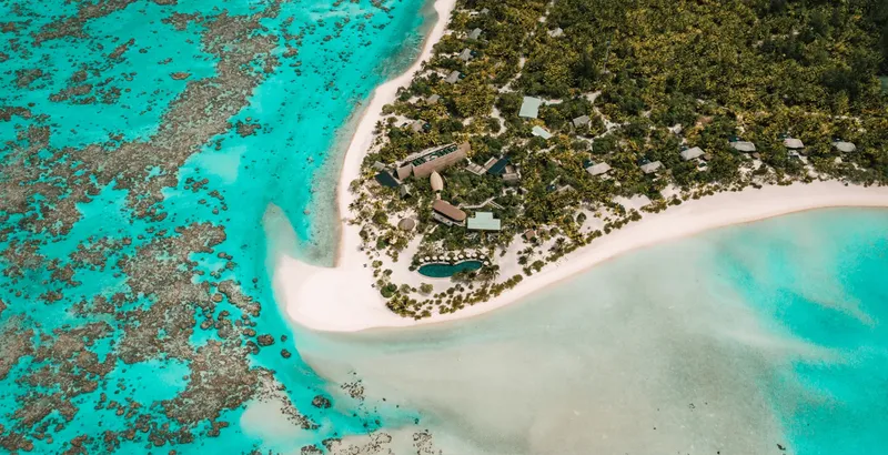 Vue aérienne d'une plage tropicale avec des bâtiments et végétation luxuriante