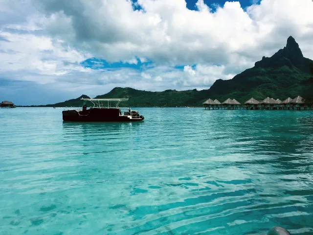 Bateau de plongée navigue sur une eau turquoise face à une montagne