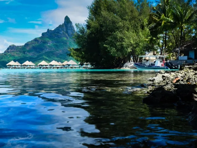 Paysage tropical avec bateau amarré, eau turquoise et montagne verdoyante