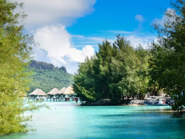 Lagune turquoise, végétation luxuriante, bungalows sur pilotis et bateaux amarrés